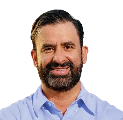 Headshot of Leo Pareja, CEO of eXp Realty, wearing a light blue shirt and smiling in front of a black background.