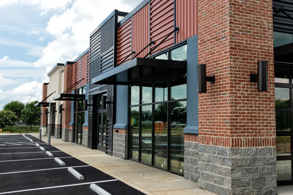 Newly constructed retail plaza with glass storefronts, brick accents, and metal awnings, ready for tenant occupancy.